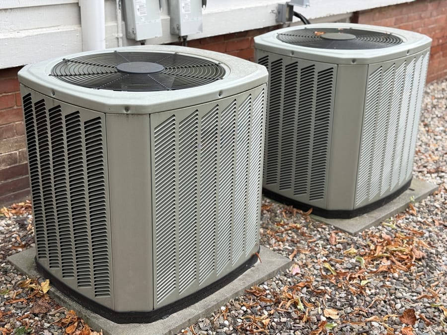 Two central air conditioning units outside of a residential home